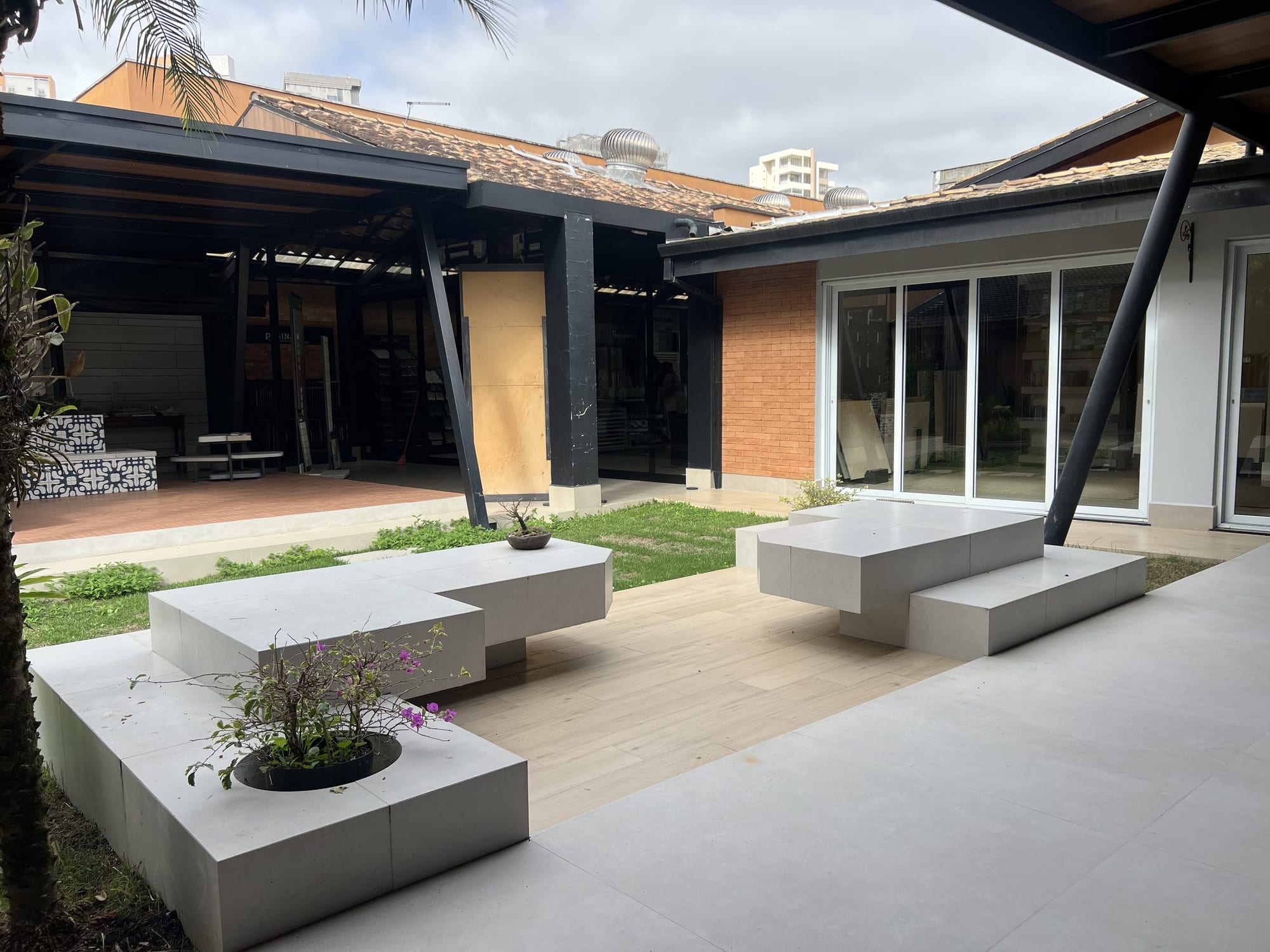 Pátio com bancos de pedra e vegetação entre os ambientes